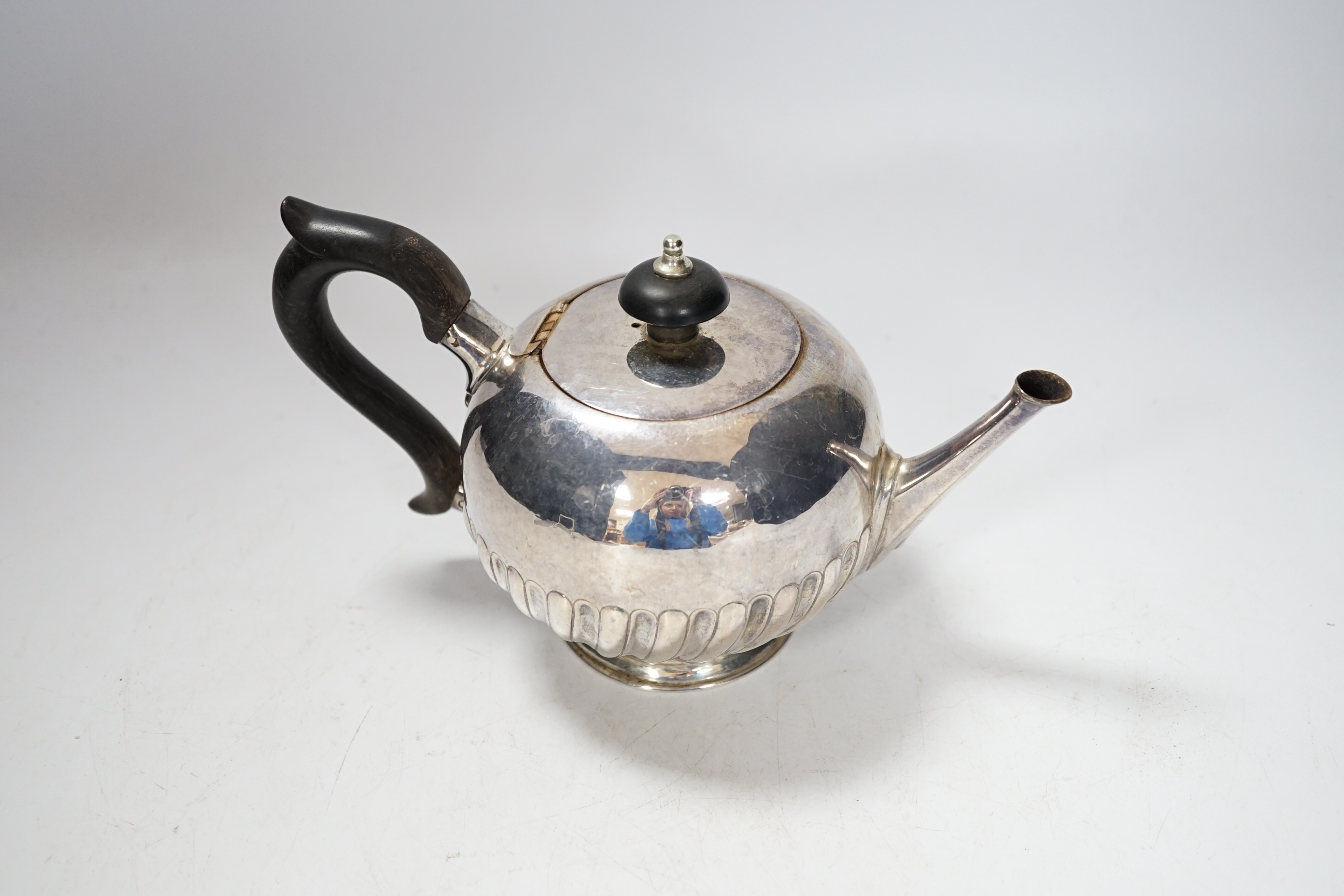 A Victorian silver bullet shaped teapot, with ebonised handle and gadrooned body, marks rubbed, London 1895, gross 321 grams